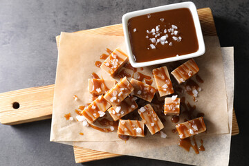 Tasty candies, caramel sauce and salt on grey table, top view