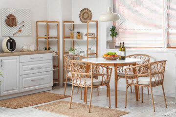 Interior of stylish kitchen with dining table, shelving unit, chairs and lamp