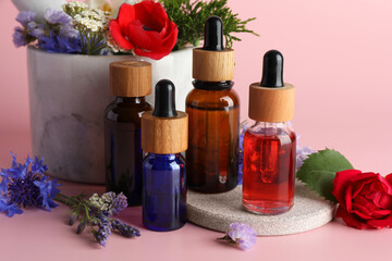 Aromatherapy. Different essential oils and flowers on pink background