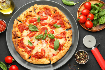 Delicious Margherita pizza, ingredients and cutter on black table, top view