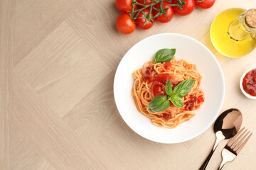 Delicious pasta with tomato sauce and basil in bowl on wooden table, flat lay. Space for text