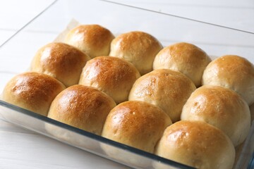 Delicious dough balls in baking dish on white wooden table