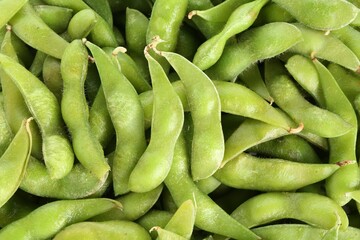 Raw green edamame pods as background, top view