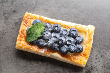 Tasty puff pastry with blueberries and mint on grey table, top view