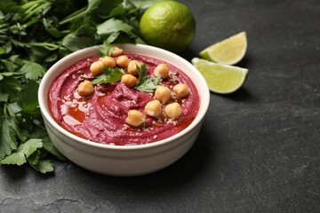 Tasty beet hummus with chickpeas in bowl on grey textured table