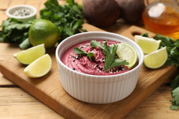 Tasty beet hummus with lime and parsley in bowl on wooden table
