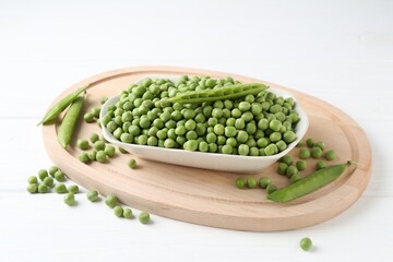 Fresh green peas and pods on white table