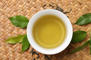 Refreshing green tea in cup and leaves on table, flat lay