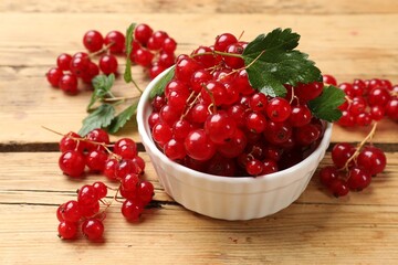 Fresh red currants and green leaves on wooden table, closeup