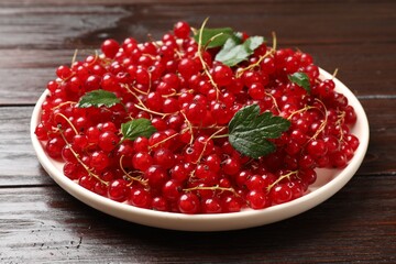 Fresh red currants and green leaves on wooden table, closeup