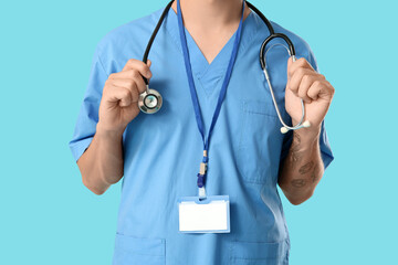 Male medical student with stethoscope and badge on blue background
