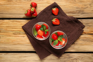 Glasses of infused water with strawberries and mint on wooden background