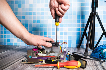 Computer technician disassembling a motherboard and recovering components