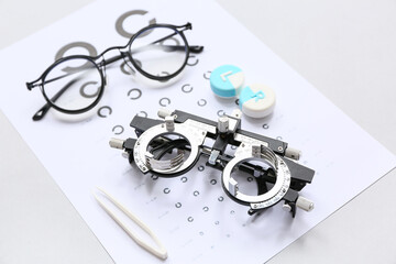 Optical trial frame with eye test chart, eyeglasses and container for contact lenses on white...