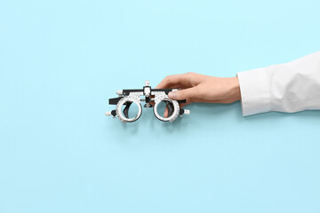 Doctor hand with optical trial frame on blue background