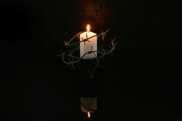 Burning candle with barbed wire on dark background. Day of Remembrance