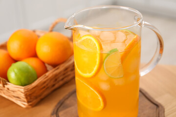 Freshly made lemonade in jug and citrus fruits on table