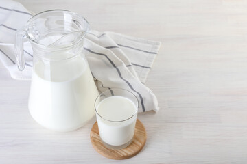Jug and glass of fresh milk on wooden table