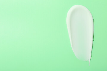 Sample of face cream on green background, top view. Space for text