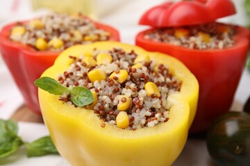 Quinoa stuffed bell peppers and basil on white table, closeup