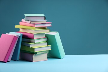 Stack of colorful books on light blue background, space for text
