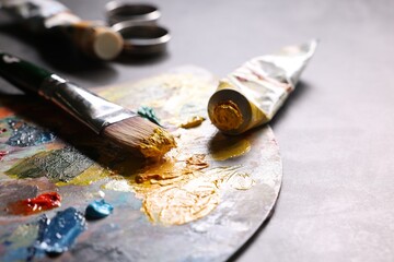 Artist's palette, brush and paints on grey table, closeup