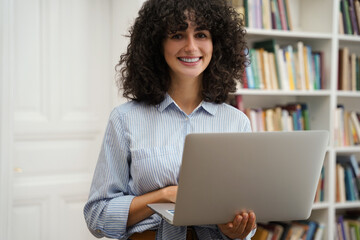 Woman student using laptop computer preparing for exams in college library