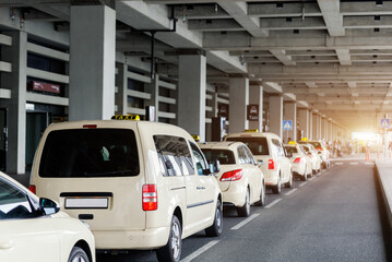 Taxi car Queue yellow taxi symbol  on roof stand waiting at parking of airport terminal or railway station Under Concrete Structure Transportation Hub. Urban street transportation comfort service