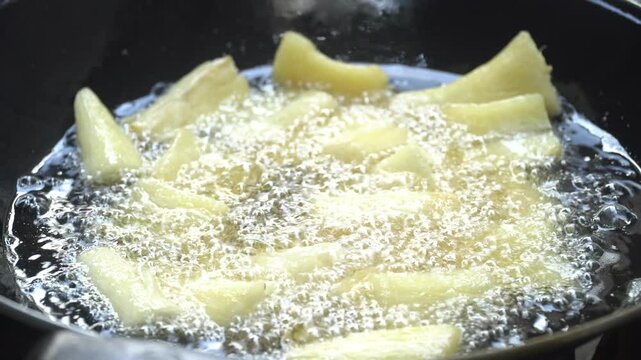 Cassava is being fried on a frying pan. Fried cassava is a traditional Indonesian food. Focus selected
