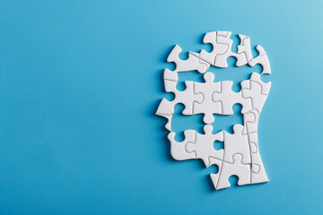 Head as a puzzle with missing puzzle pieces on blue background with space for text or inscriptions, top view