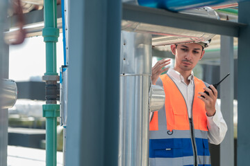 Male engineer inspects air and water pipelines in the engineering system area of ​​the factory outside where various pipelines are designed modernly. Technicians work in the petrochemical industry.