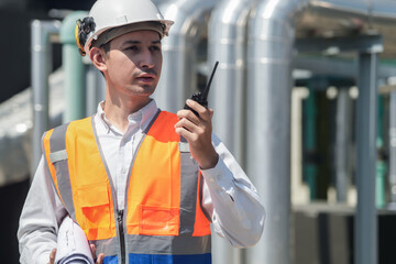 Male engineer inspects air and water pipelines in the engineering system area of ​​the factory outside where various pipelines are designed modernly. Technicians work in the petrochemical industry.