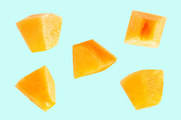  Falling slices of cantaloupe melon on light green background.