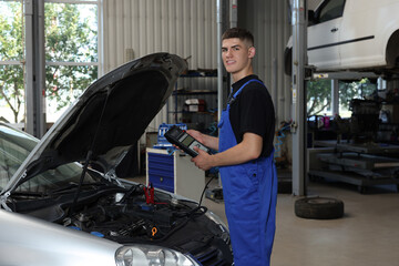 Young auto mechanic fixing car at automobile repair shop