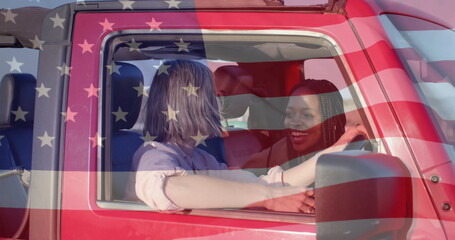 Image of flag of usa over happy diverse women in car by beach in summer