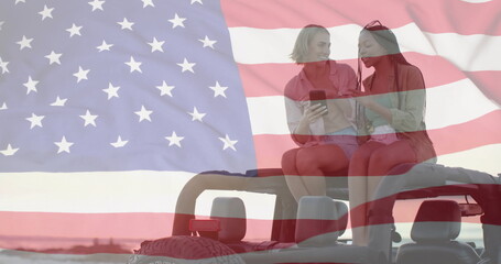 Image of flag of usa over happy diverse women on car by beach in summer