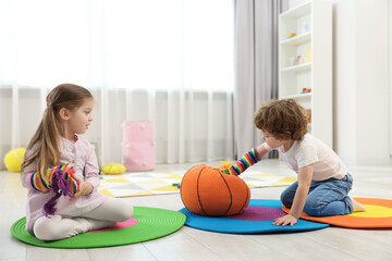 Cute little children playing with funny sock puppets and soft toy ball in kindergarten