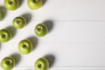 Fresh ripe green apples on white wooden table, flat lay. Space for text
