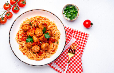 Spaghetti with meatballs in marinara sauce, top view, white table