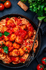 Italian spaghetti in bolognese sauce with meatballs, black table background, top view