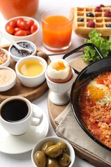 Cup of coffee and different meals served for breakfast on white table, closeup