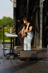 Female performer on stage. Portrait of woman playing a guitar.