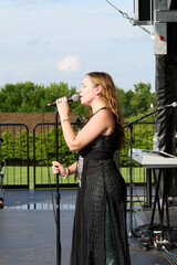 Female performer on stage. Portrait of woman singing at a microphone.