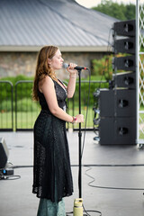 Female performer on stage. Portrait of woman singing at a microphone.