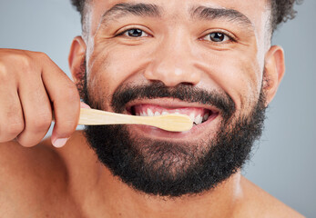 Man, portrait and brushing teeth with toothbrush on studio background for dental care, plaque...