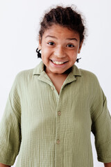 Smiling young boy in green shirt standing confidently against white background