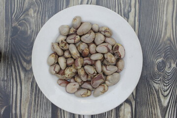 Jackfruit seeds, or Beton in Javanese, on a white plate on a wooden brown background. The jackfruit seeds can be boiled to be eaten. Jackfruit seeds have many benefits and antioxidants.