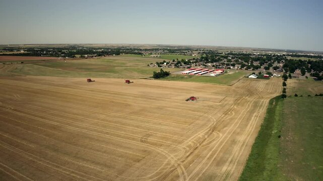 Drone shot of a farming combine harvesting the wheat in a large agricultural field.