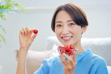 自宅でミニトマトを食べる女性　カメラ目線
