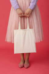 Woman in pink skirt with cotton bag on pink background